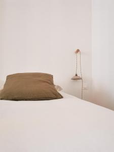 a white bed with a pillow and a lamp at Appart Cozy - cœur historique de Moissac in Moissac +11 photos