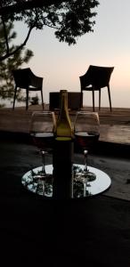 a bottle of wine and two glasses on a table at Cabaña Tamanique in Tamanique