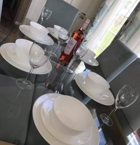 a table with white plates and a bottle of wine at Lemon Tree Lodge in Morpeth