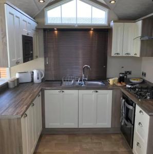 a kitchen with white cabinets and a sink and a window at Lemon Tree Lodge in Morpeth