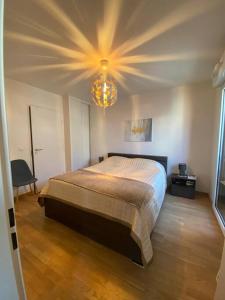 een slaapkamer met een groot bed en een kroonluchter bij Luxury & Cosy apart with balcony Eiffel Tower view in Issy-les-Moulineaux