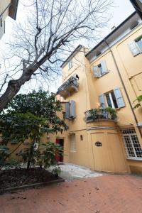 a large yellow building with a balcony and a tree at RESIDENZA ALDROVANDI SUITE in Bologna