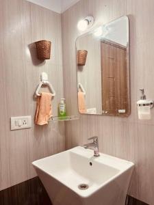 ein Badezimmer mit einem weißen Waschbecken und einem Spiegel in der Unterkunft Wind and Wave Villa No 2, 2BHK Near Pondy Auroville Pondicherry in Marakkānam