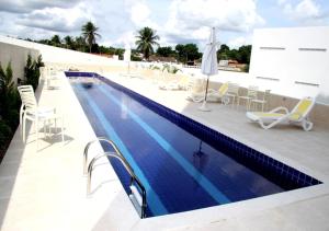 a swimming pool with chairs and umbrellas on a building at Hotel Áster in Alagoinhas
