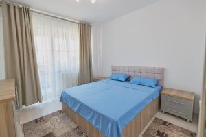 sypialnia z łóżkiem z niebieską pościelą i oknem w obiekcie Alessandro Home 5 Luxury Centru Palas Mall Iași Q Residence w Jassach