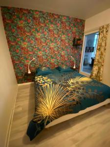 a bedroom with a bed with a floral wall at Gîte Les Domaines in Avallon