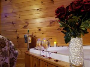 賽維爾維爾的住宿－Little Cabin All To Yourself，一张桌子,上面放着酒杯,还有一个花瓶,上面放着玫瑰花