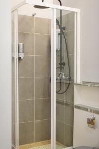 La salle de bains est pourvue d'une douche avec une porte en verre. dans l'établissement Patras' Hitech Apartment, à Patras