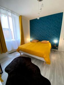 a bedroom with a yellow bed with a blue wall at Gîte Les Domaines in Avallon