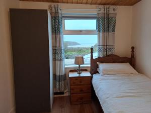 a bedroom with a bed and a large window at Blaneys Coastal Cottage in Mountcharles