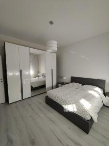 Dormitorio blanco con cama y espejo grande en Domus Anna, en Montegrotto Terme
