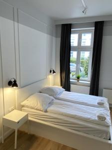 a white bed in a bedroom with a window at RJ Family Sopot in Sopot