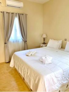 a bedroom with a large white bed with a window at Aegean Muses in Leipsoi