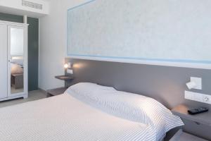 a bedroom with a white bed and white walls at Aparthotel Puerto Cala Vadella in Cala Vadella