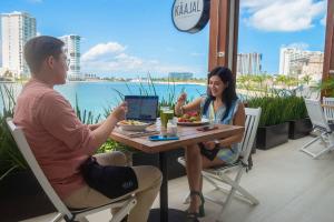 a man and woman sitting at a table with a laptop at Renaissance Cancun Resort & Marina in Cancún