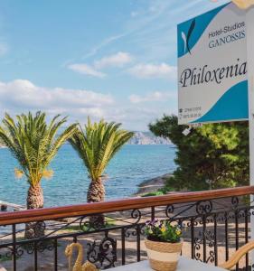 a balcony with palm trees and the ocean at Philoxenia Ganossis in Ermioni