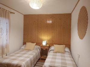 Duas camas num quarto com paredes de madeira em Casa Rural Castellanos em Huelamos