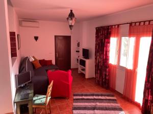 uma sala de estar com um sofá e uma cadeira vermelha em Casandalusí em Frigiliana