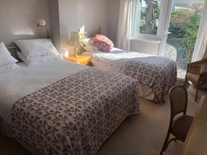 a bedroom with two beds and a window at Southcote Accommodation in Tintagel