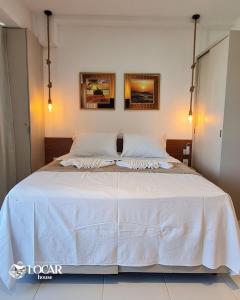 1 dormitorio con 1 cama blanca y 2 almohadas en Flat luxo no Mana Beach em Muro Alto 4 pessoas, en Porto de Galinhas