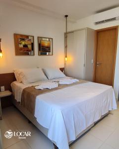 una camera da letto con un grande letto con lenzuola bianche di Flat luxo no Mana Beach em Muro Alto 4 pessoas a Porto De Galinhas