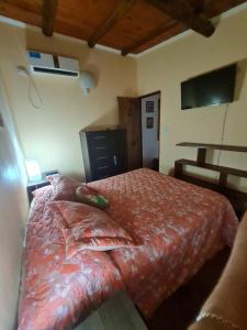 a bedroom with a bed with a red comforter at Cabaña Alma 2 in Villa Carlos Paz