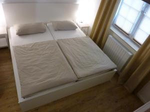 ザンクト・ペーター・オルディングにあるFerienwohnung Nis Randersのベッド(白いシーツ付)、窓が備わります。