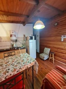 a kitchen with a table and a refrigerator in a room at Cabaña Alma 2 in Villa Carlos Paz