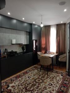 een keuken met zwarte kasten en een tafel met een tapijt bij apartment seven A in Tasjkent