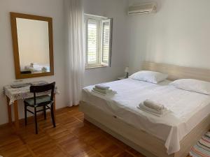 a bedroom with a bed and a mirror and a chair at Rooms Jelena in Dubrovnik