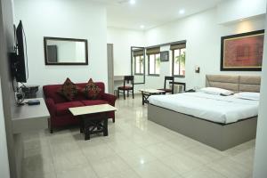 a bedroom with a bed and a couch and a tv at ELGIN SUITES in Kolkata