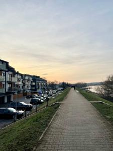 a sidewalk next to a river with parked cars at Apartments Sleep & GO Modlin Airport in Nowy Dwór Mazowiecki