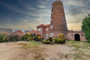 an old brick building with a tall tower at The Windmill by TJ Serviced Property 