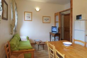 a living room with a table and a green couch at Gîte CAMPANULES - 5 personnes - "Les Gites du Chalet" à Autrans in Autrans