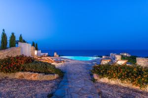 a pathway leading to a swimming pool with flowers at Blue Caves Villas - exceptional Villas with private pools direct access to the sea in Koríthion