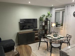 a living room with a table and a flat screen tv at Apartament Błogi Sen III - komfortowy nocleg w spokojnej lokalizacji in Zabrze
