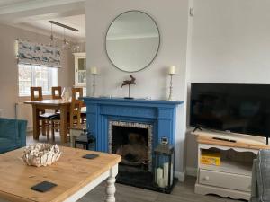 a living room with a blue fireplace and a tv at Klara's House in West Mersea