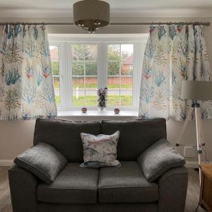 a couch in a living room with two windows at Klara's House in West Mersea +33 photos
