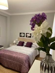 a bedroom with a bed with purple and white flowers in a vase at Apartamento Venus in Salar