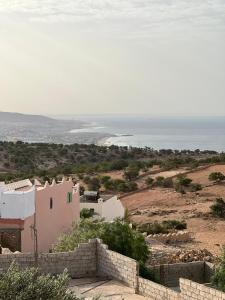 a house on a hill with the ocean in the background at La colina House taghazout in Taghazout