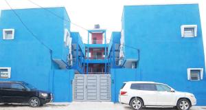 dos autos estacionados frente a un edificio azul en Residence MaryHouse en Cotonú