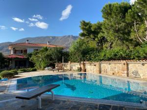 una piscina con panchina di fronte a una casa di Kineta luxury House a Kineta
