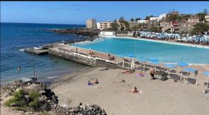 a group of people on a beach with a swimming pool at Pino's Vivienda Vacacional in Costa Del Silencio