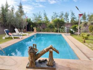 a swimming pool with a statue in front of it at villa Marrakech piscine privée in Marrakesh