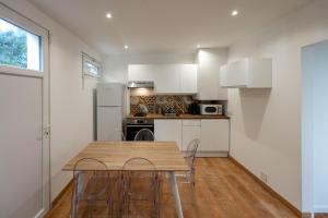 eine Küche mit weißen Schränken sowie einem Holztisch und Stühlen in der Unterkunft Maison Ohana 4-6 pers dans résidence Privée près de la Plage in Canet-en-Roussillon