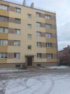 een groot geel gebouw met een parkeerplaats ervoor bij Ukstiņa Holiday apartment in Liepāja