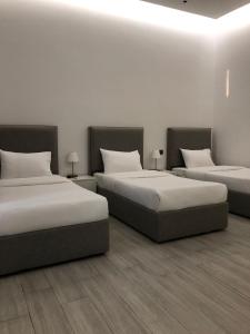 three beds in a room with white walls at شاليهات بالي ان الفندقية in Jeddah