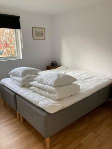 uma cama com lençóis brancos e almofadas em Långasand em Heberg