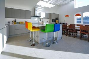 a kitchen with colorful bar stools and a dining room at Unique 5BD Farm House Perfect for Relaxing in Ipswich