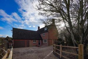 una casa rossa con una recinzione di fronte di Unique 5BD Farm House Perfect for Relaxing a Ipswich